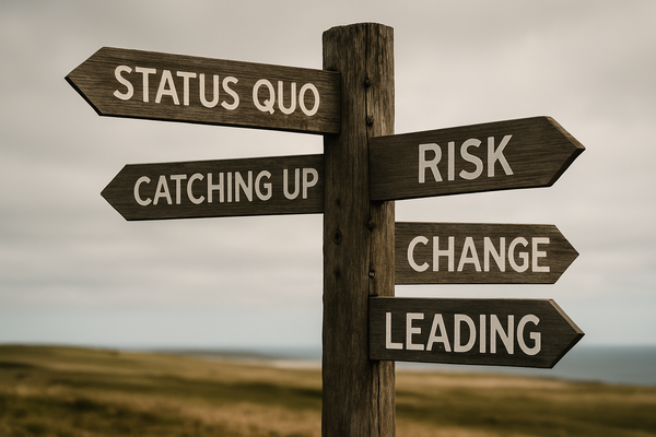 A wooden signpost in a wide landscape with signs pointing to "Status Quo," "Risk," "Change," and "Leading"—symbolizing choices organizations face in times of transformation.